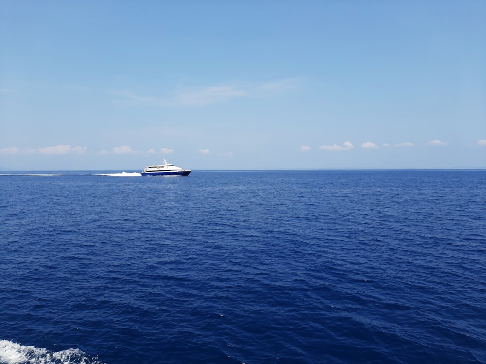 昼間の青空の下、海に浮かぶ白と黒のボート