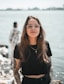 woman in black crew neck t-shirt wearing brown framed eyeglasses standing on rocky shore during