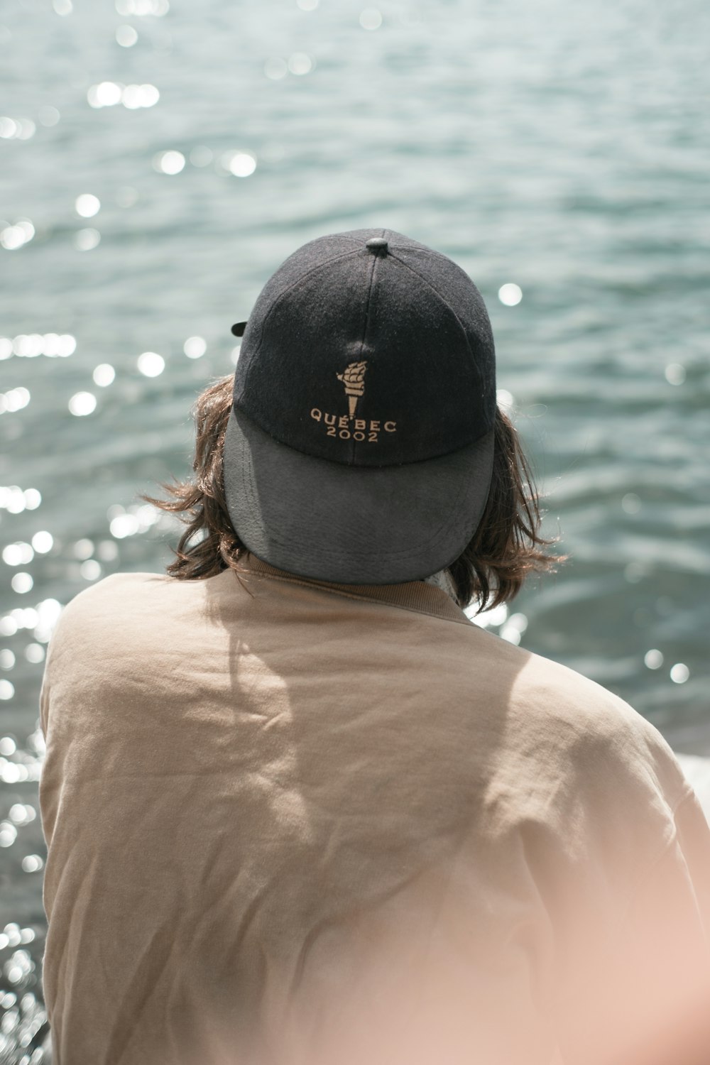 woman in black fitted cap and orange shirt looking at the sea during daytime