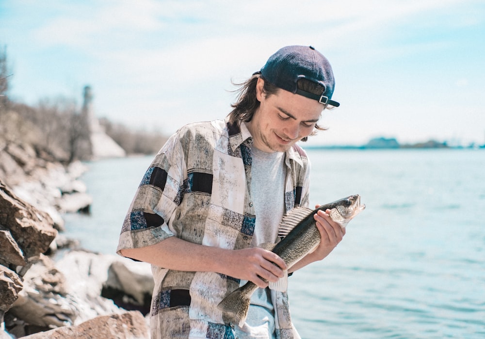 woman in white and black plaid shirt holding fish