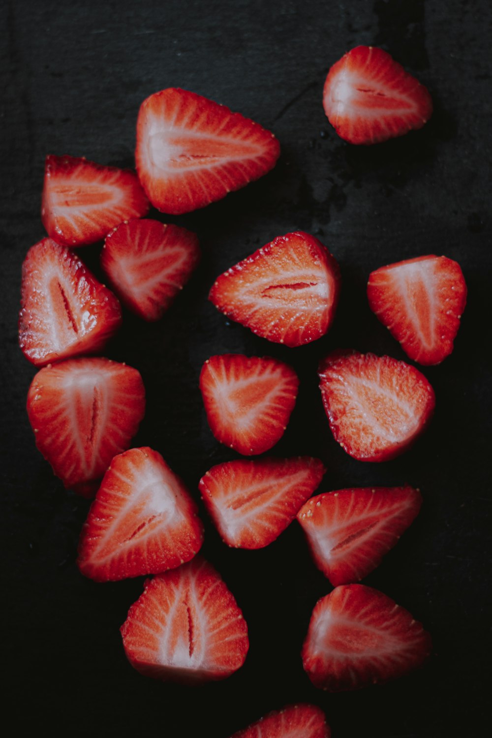 in Scheiben geschnittene Erdbeeren auf schwarzer Oberfläche