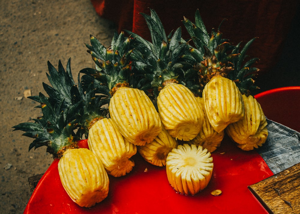 Fruits d’ananas jaunes et verts sur assiette en plastique rouge