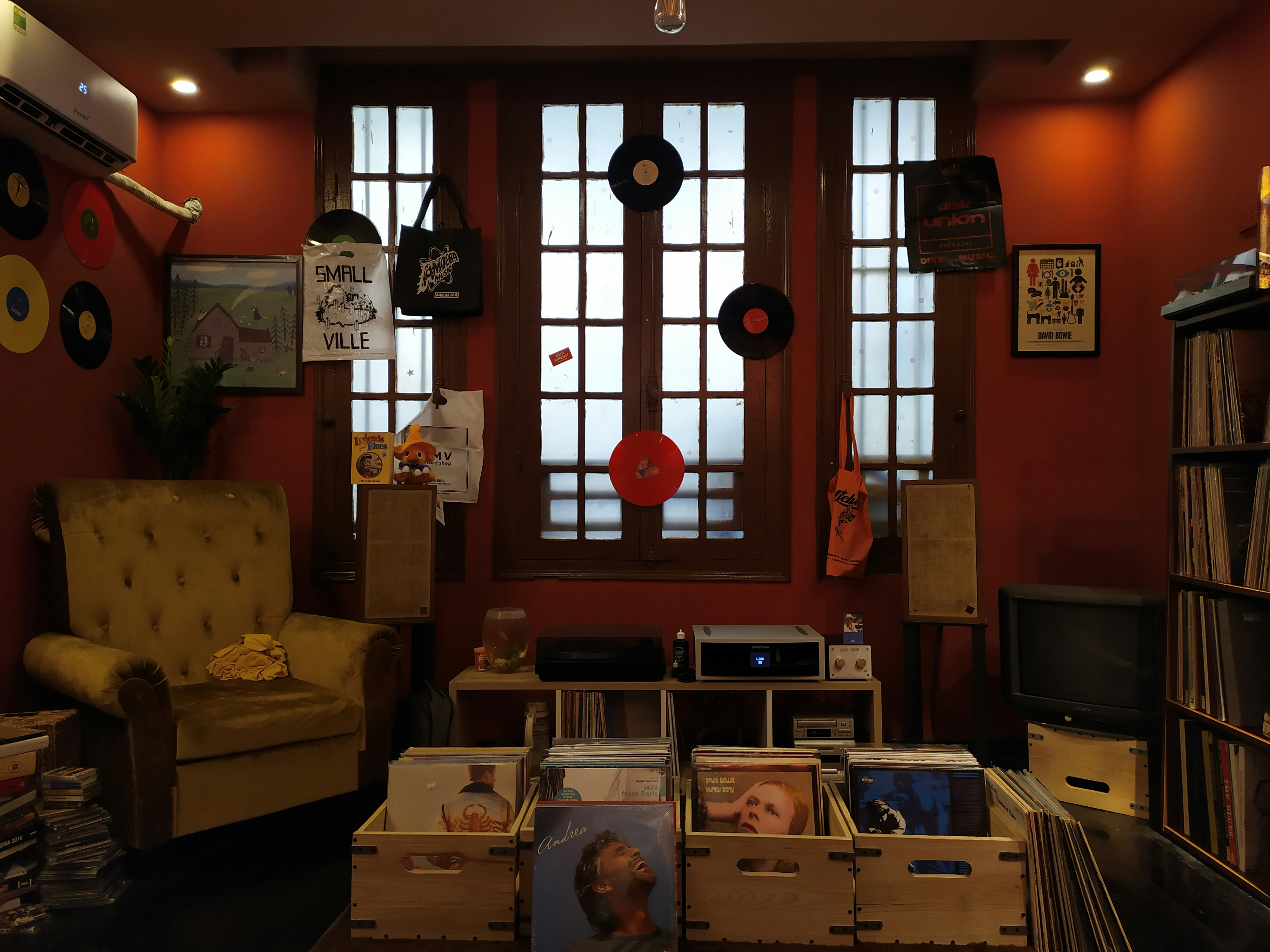 Vintage vinyl records stacked in a crate with warm lamp light in a cozy music room