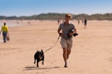 woman in gray long sleeve shirt and white shorts holding black short coated dog during daytime