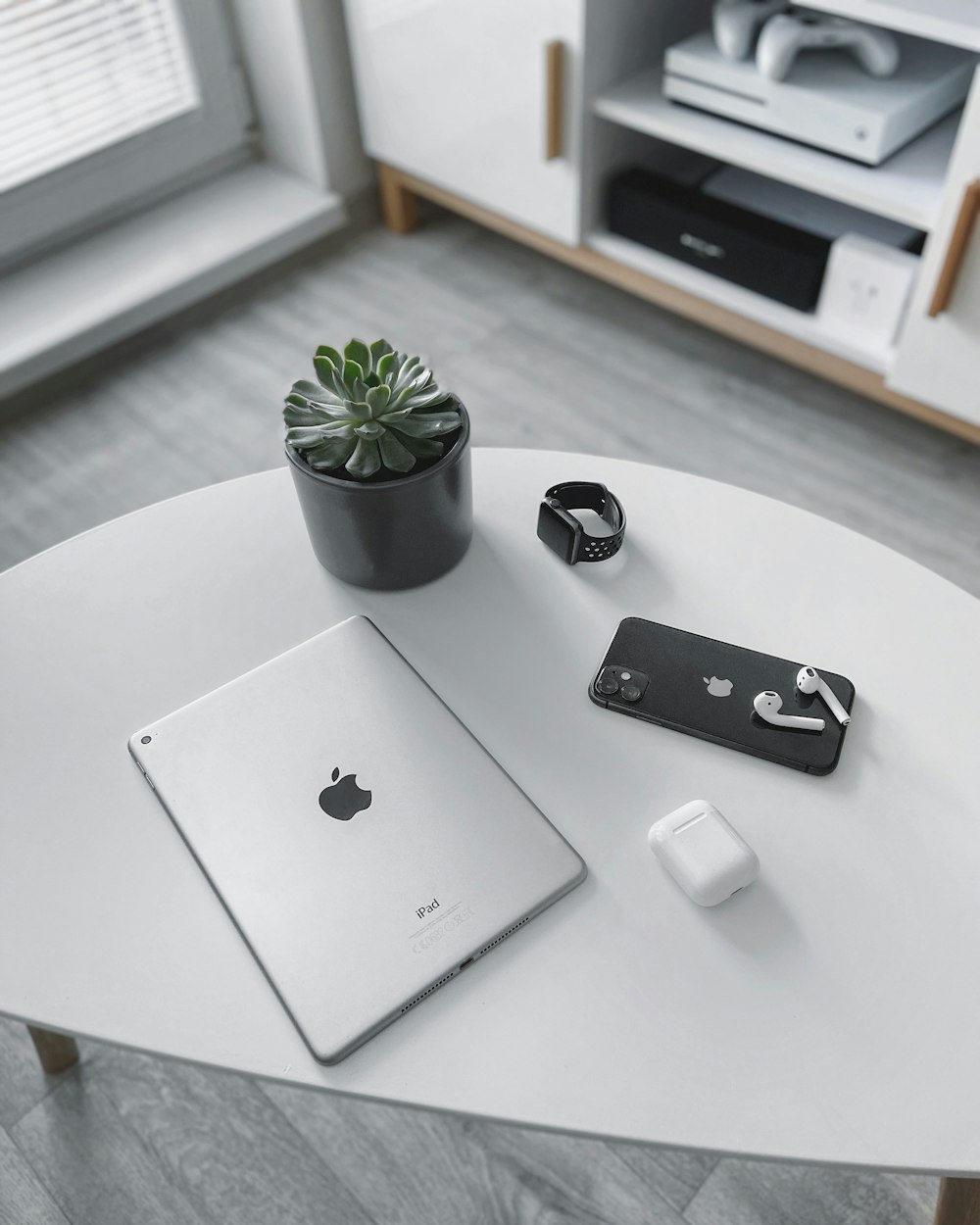 MacBook d'argento accanto al topo magico della mela bianca e alla pianta verde sul tavolo bianco