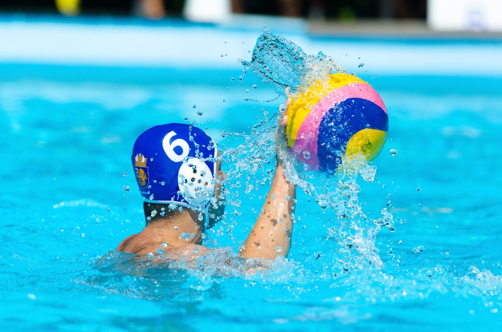 personne nageant dans la piscine avec ballon gonflable multicolore