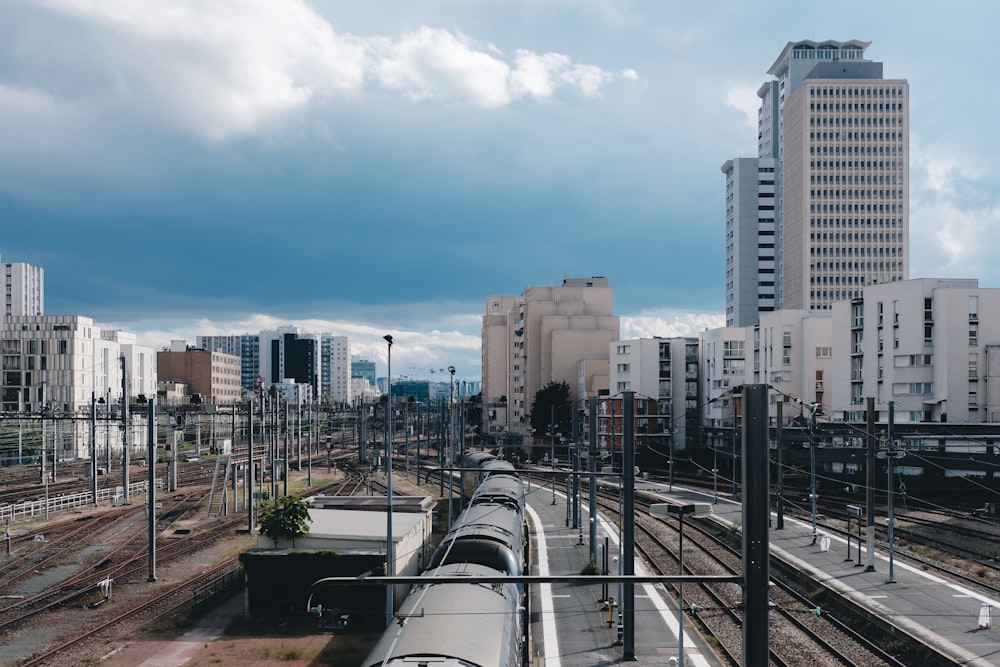 gray metal train rail near city buildings during daytime