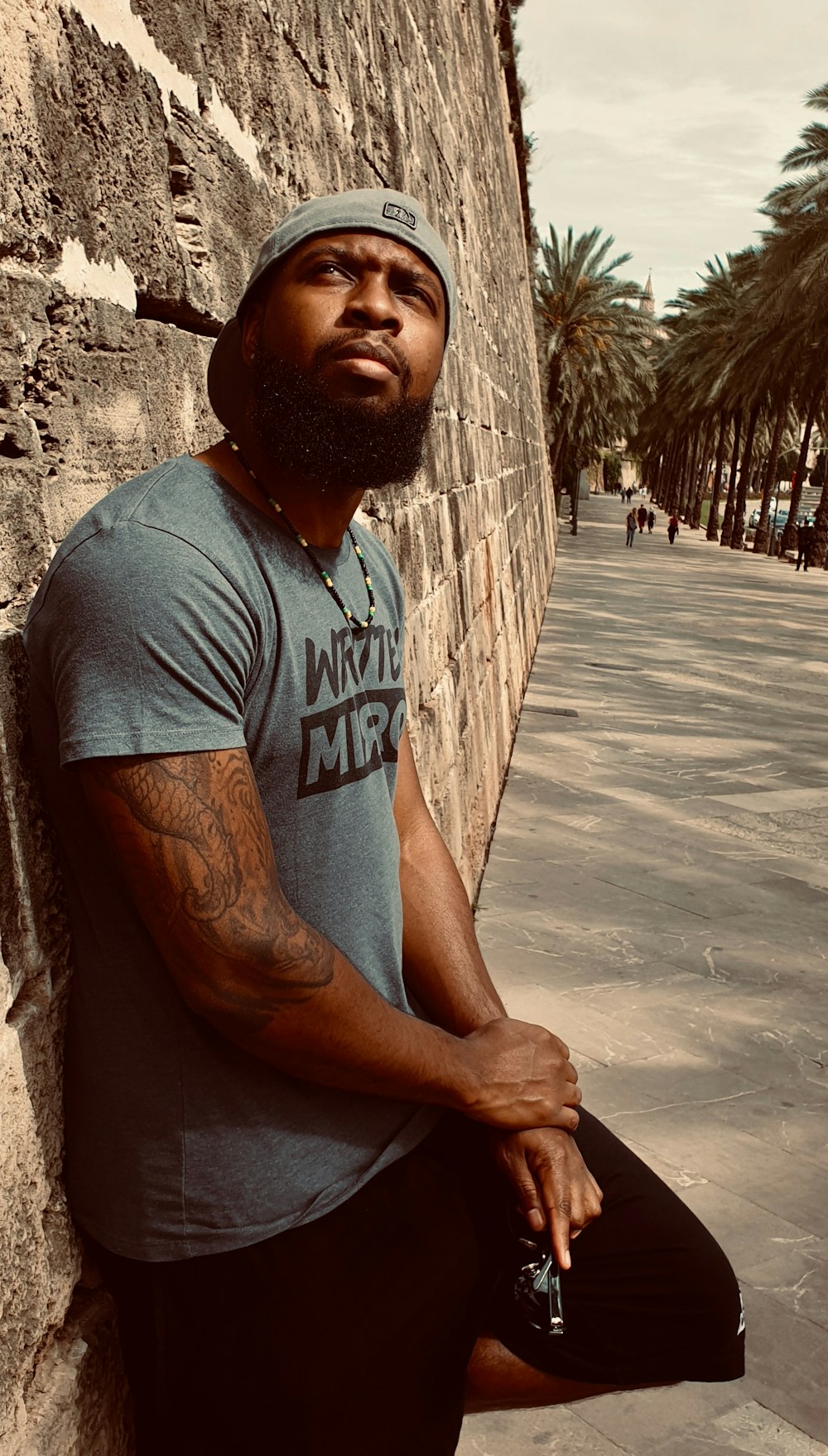 man in gray crew neck t-shirt leaning on brown tree trunk during daytime