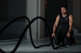 woman in black tank top and black pants sitting on black exercise equipment