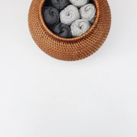 A small desktop basket filled with colorful yarn balls beside a cozy armchair.