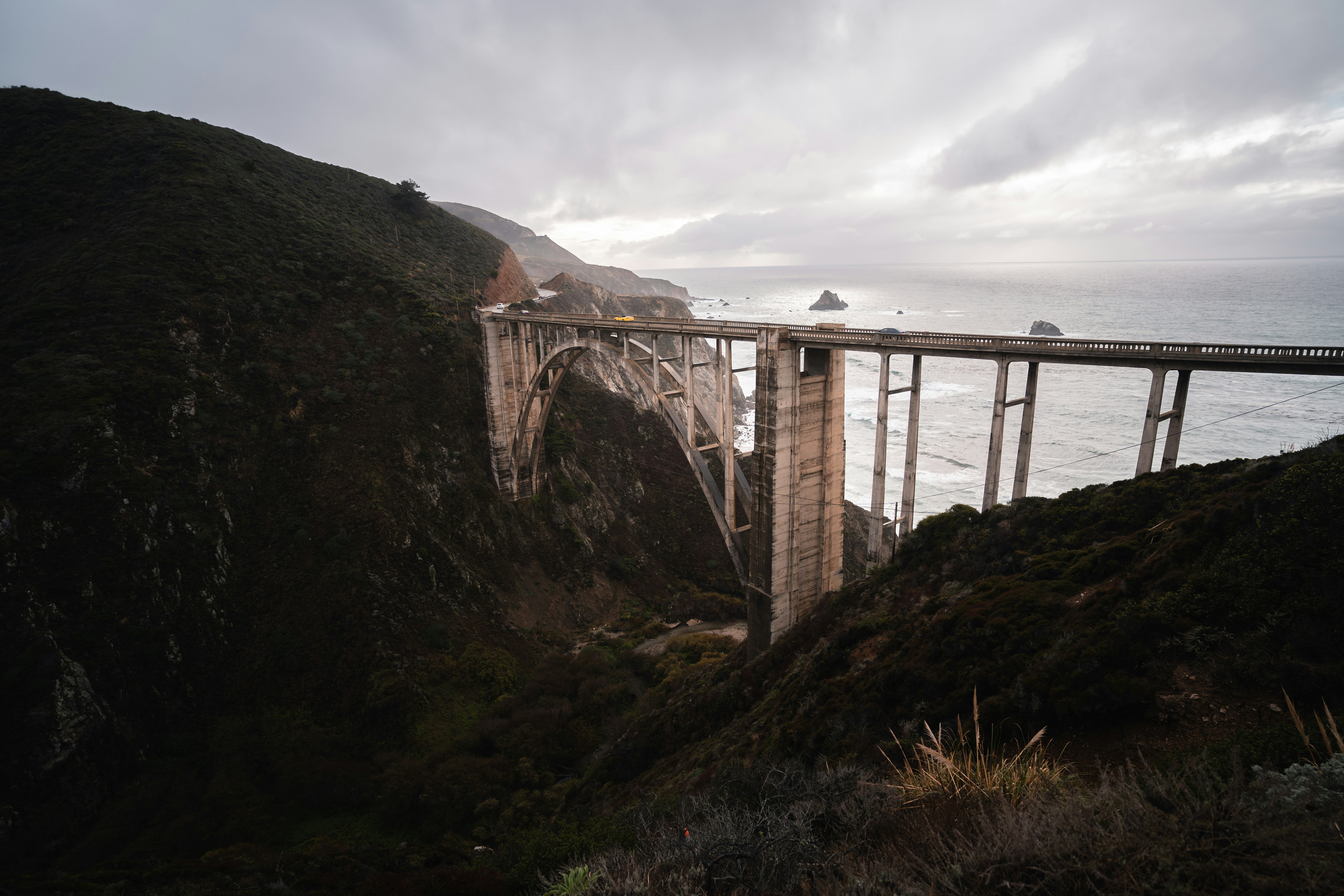 Pont brun sur la montagne verte sous les nuages blancs pendant la journée