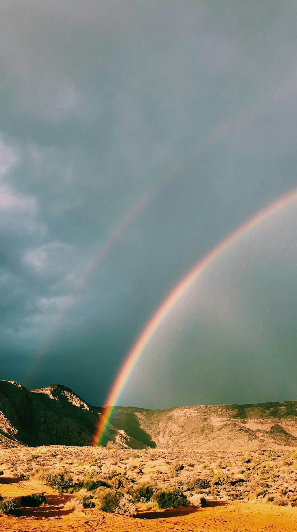 green mountain under rainbow during daytime