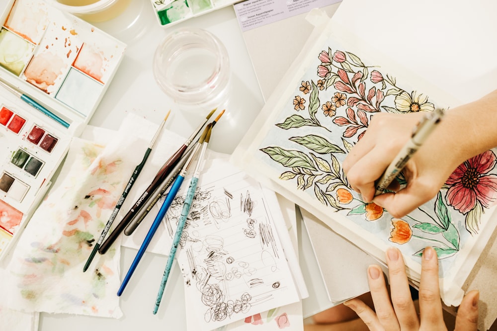 person holding white and red floral card