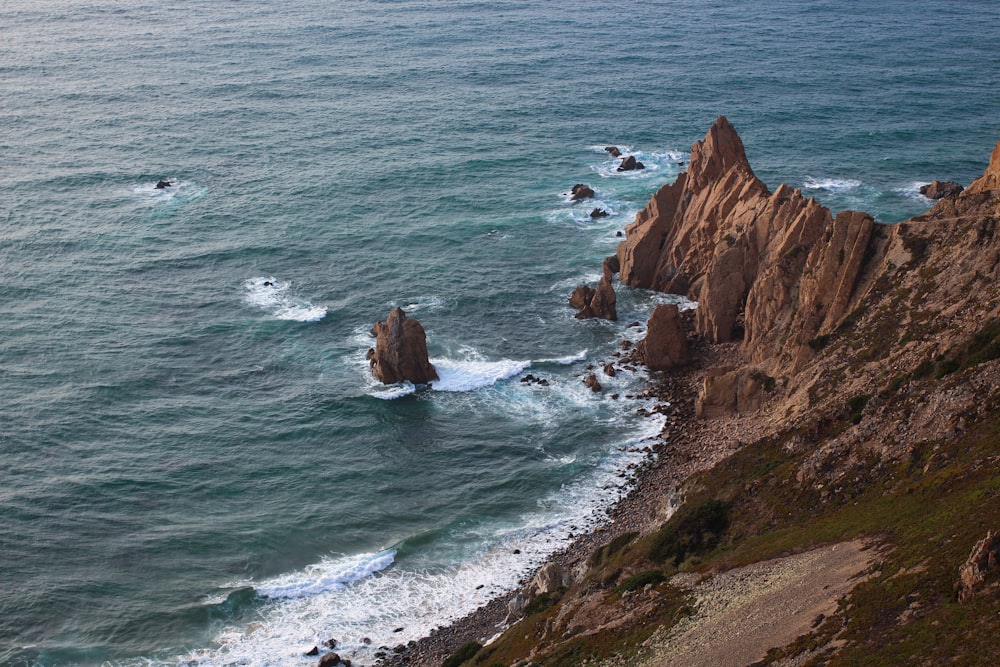 brown rock formation beside body of water during daytime