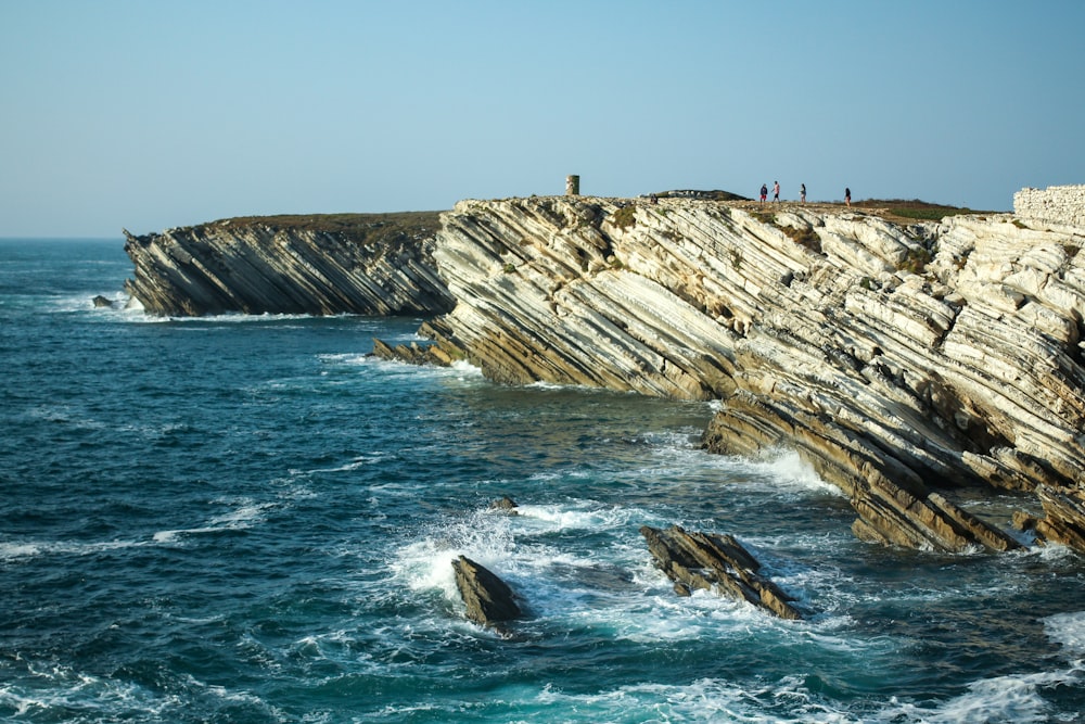 people standing on rocky shore during daytime