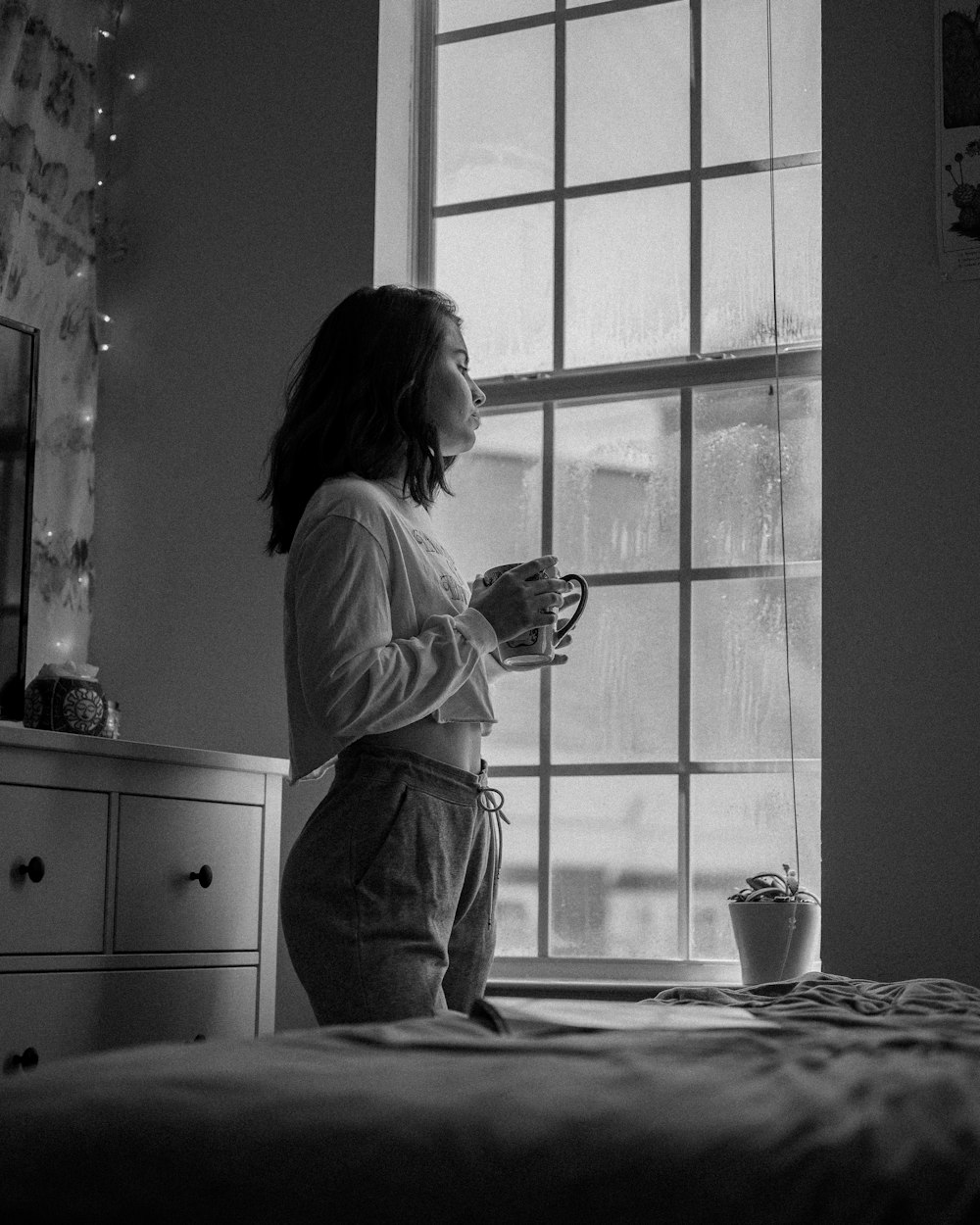 woman in white long sleeve shirt holding mug in grayscale photography