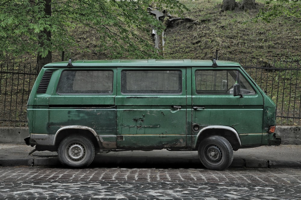 green van parked on gray concrete road during daytime