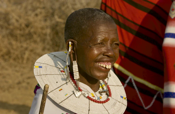 A close-up of a smiling traveler admiring a vibrant Maasai warrior’s traditional beadwork.