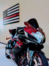 A sleek sports motorcycle parked inside a workshop with red and black racing-themed decor.