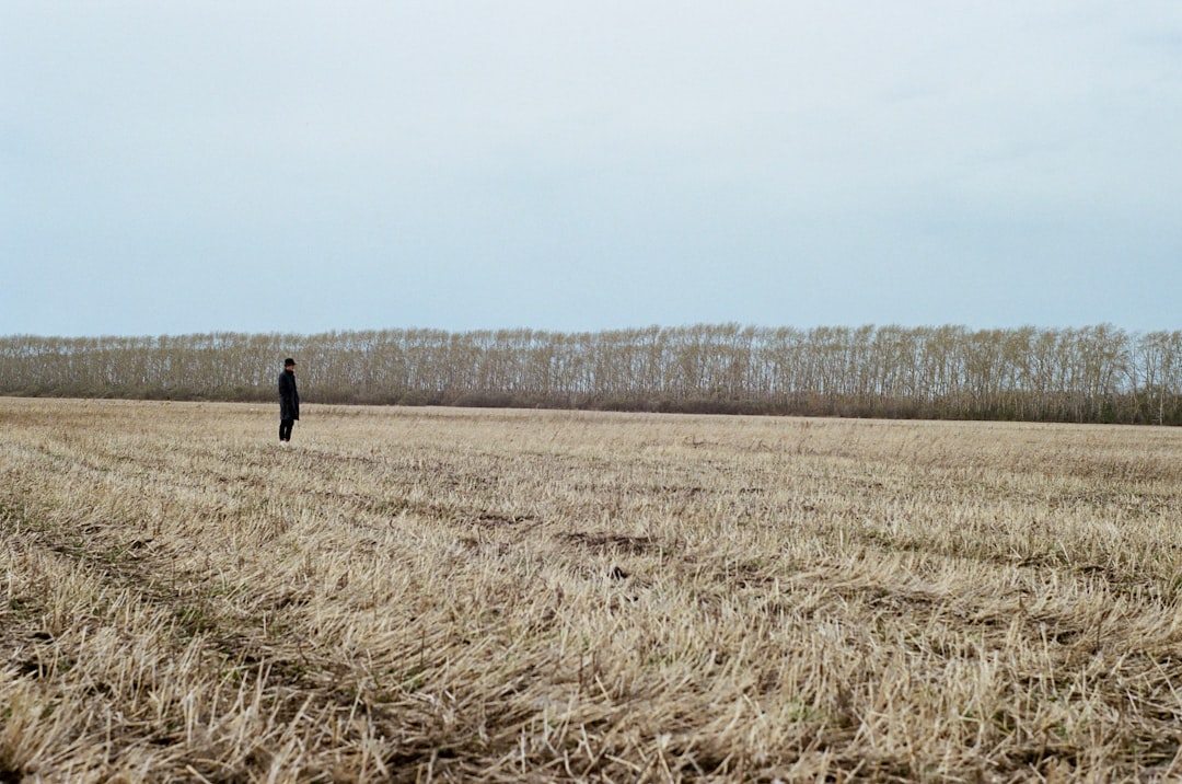 person in black jacket walking on brown grass field during daytime