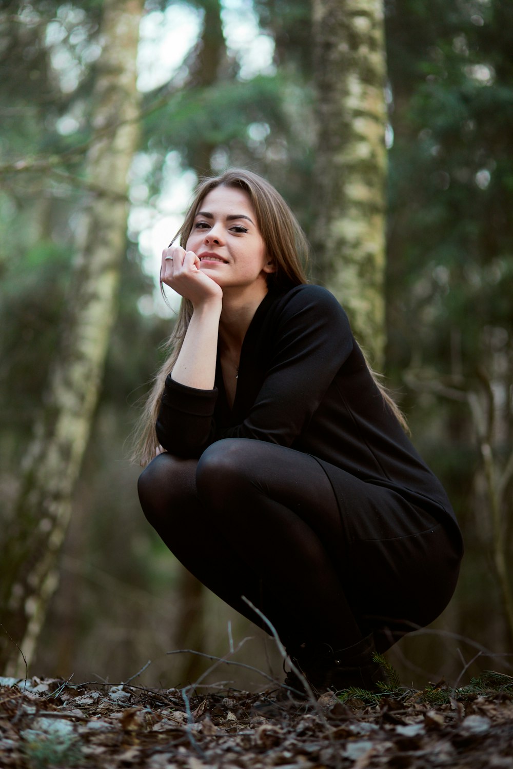 woman in black long sleeve shirt and black pants sitting on tree branch