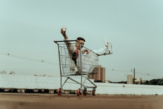 woman in white jacket and blue denim jeans riding on shopping cart during daytime