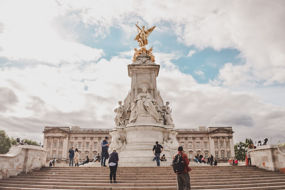 people walking on sidewalk near statue of man riding horse during daytime