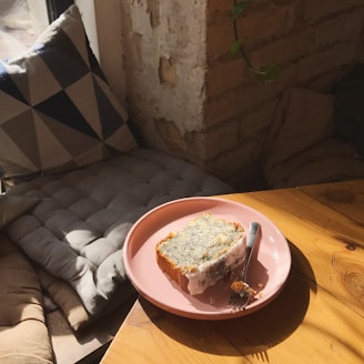 Close-up of a golden lemon pound cake slice topped with glossy lemon glaze and a dusting of powdered sugar.