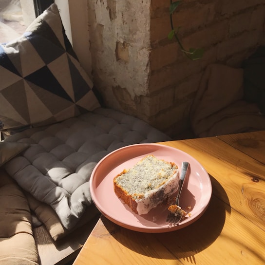 Close-up of a golden lemon pound cake slice topped with glossy lemon glaze and a dusting of powdered sugar.