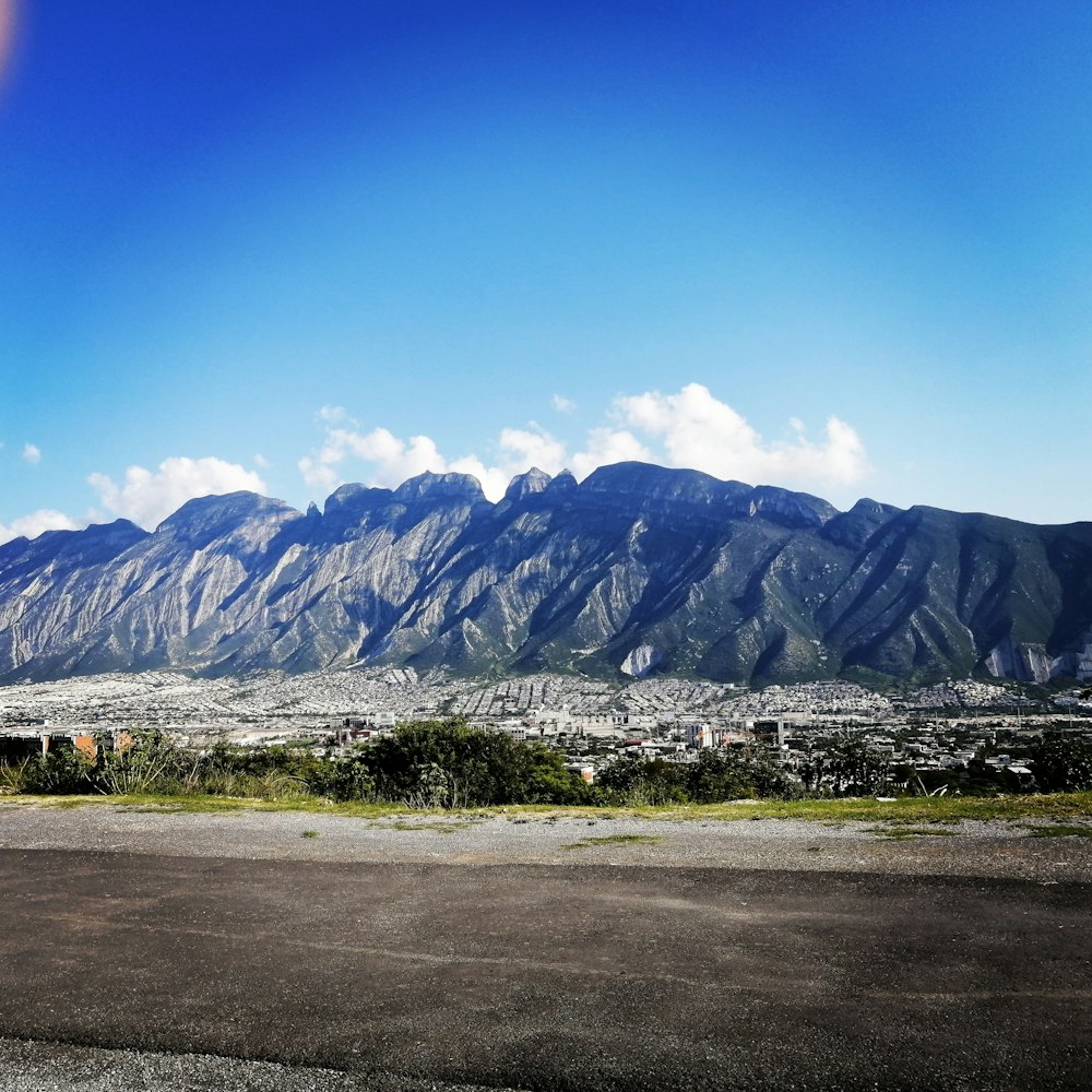 昼間の青空の下に灰色と白の山々