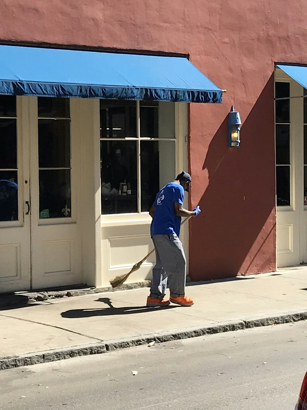 man in blue t-shirt and blue denim jeans holding red and yellow broom