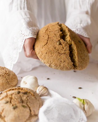 Hands arranging artisanal bread and fresh produce for a styled social media photo shoot.