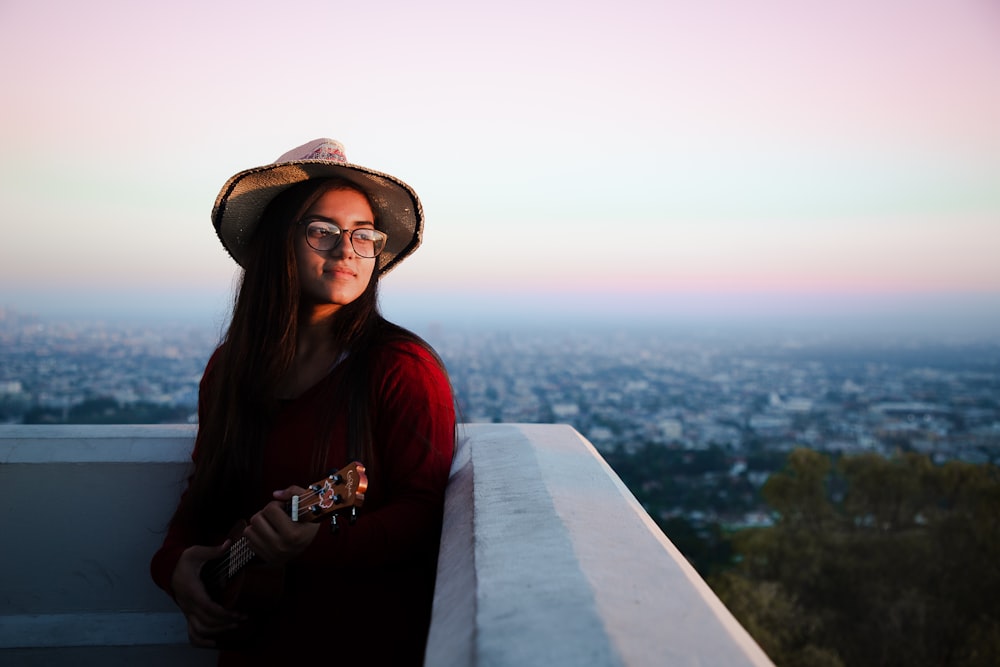 woman in red long sleeve shirt and brown hat standing on top of a building during