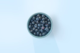 A vibrant bowl filled with wild blueberries surrounded by fresh ingredients.