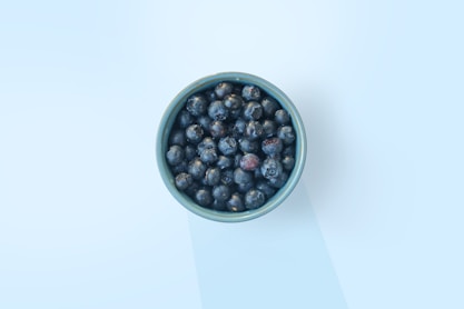 A vibrant bowl filled with wild blueberries surrounded by fresh ingredients.
