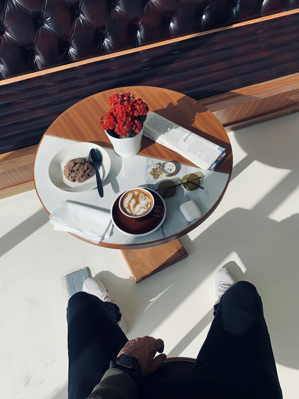 person in black pants sitting by the table with food on plate