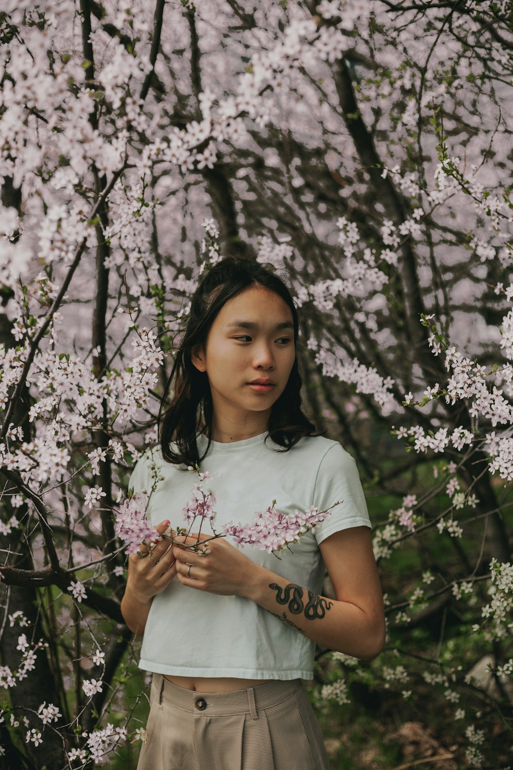 woman in purple crew neck t-shirt standing under white flowers