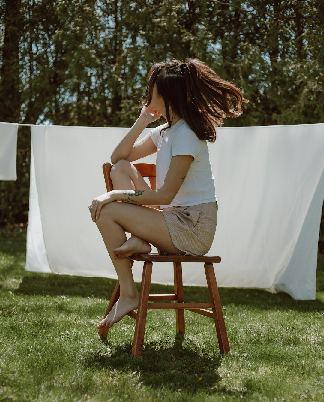 woman in white tank top sitting on brown wooden chair