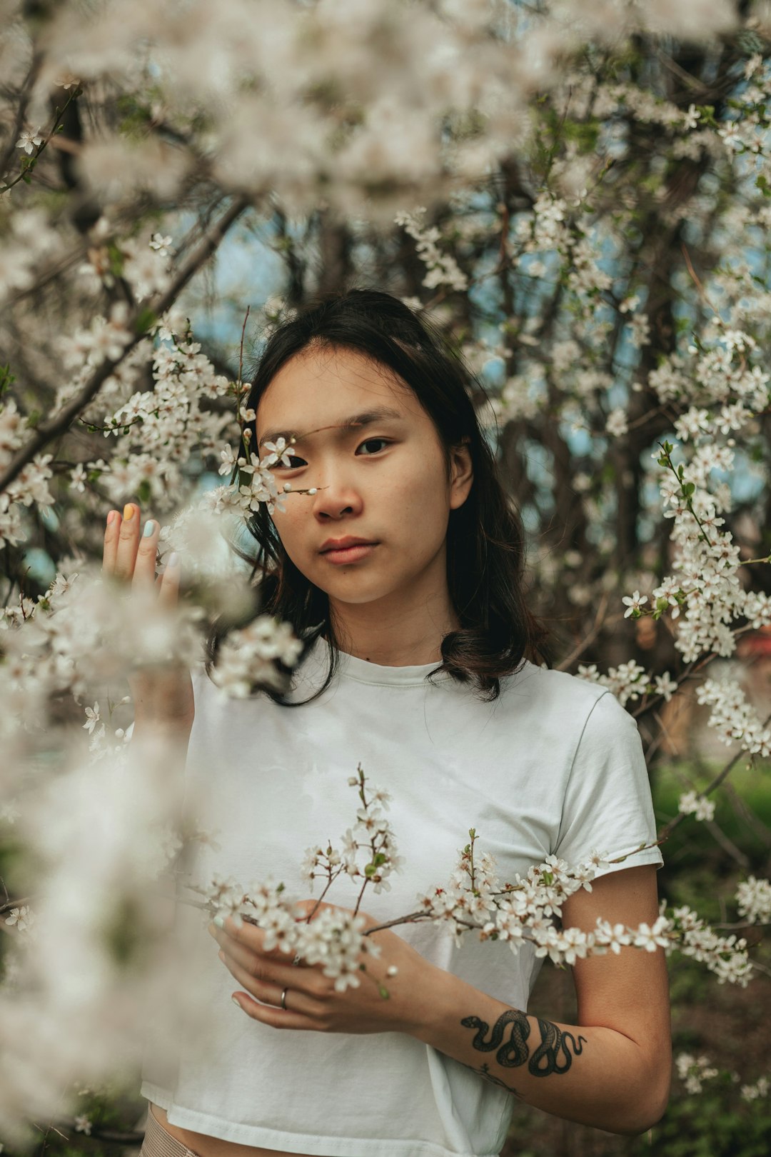 woman in white crew neck t-shirt standing under white flowers