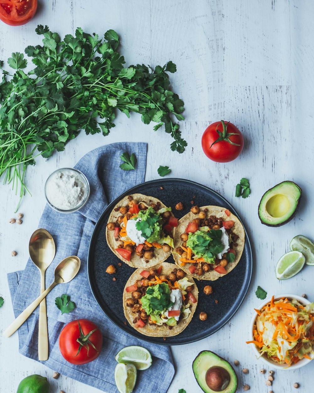 Pizza con hojas verdes y tomate rojo en plato de cerámica negra