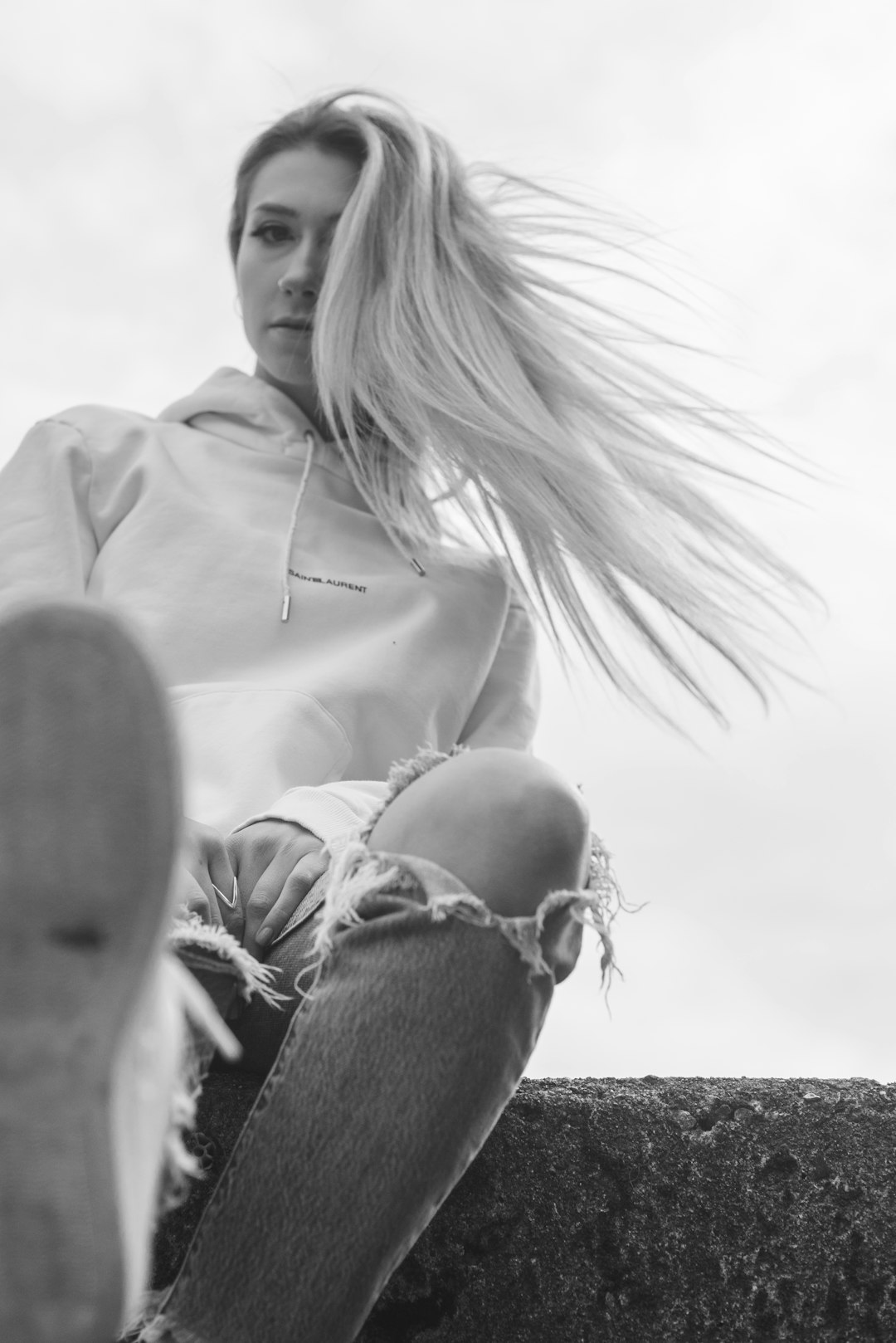 woman in white dress shirt and blue denim jeans sitting on sand