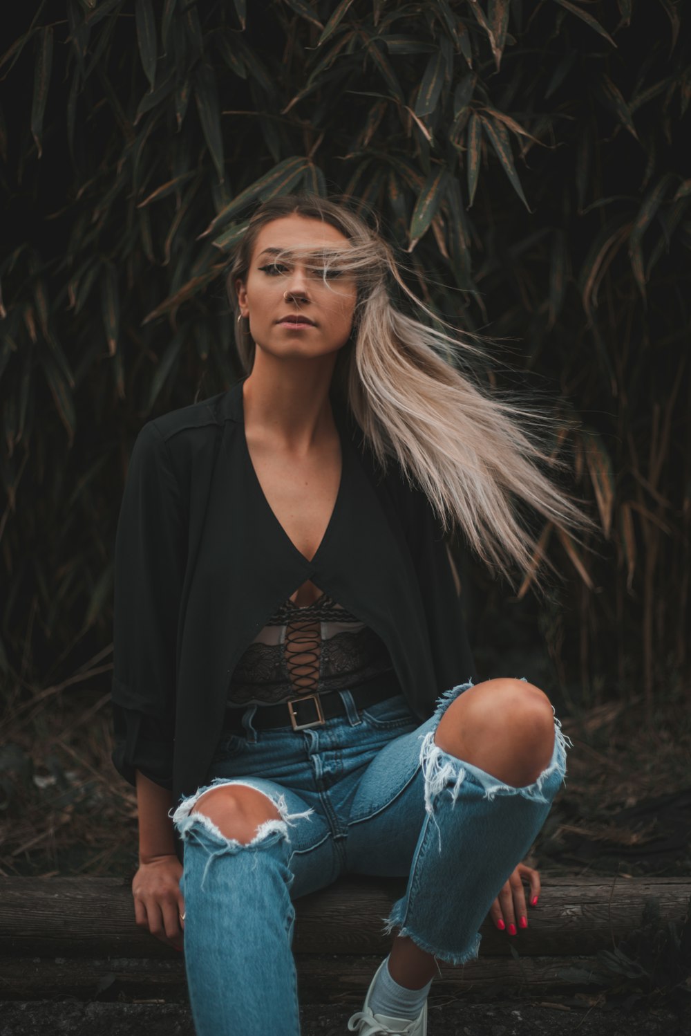 woman in black blazer and blue denim jeans sitting on ground