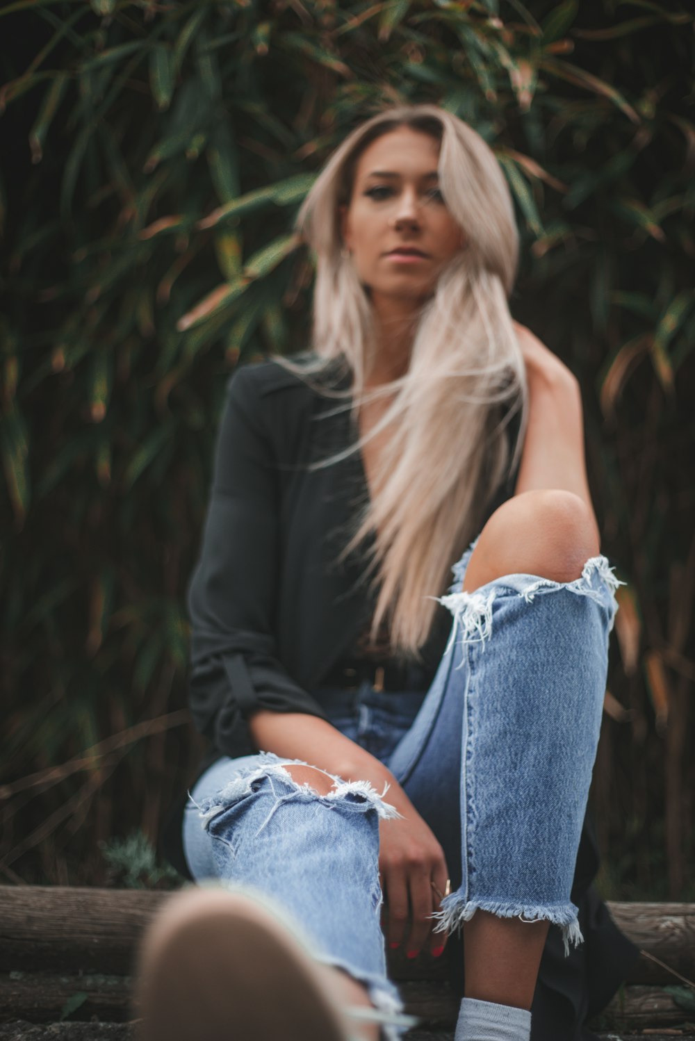 woman in black blazer and blue denim jeans sitting on ground