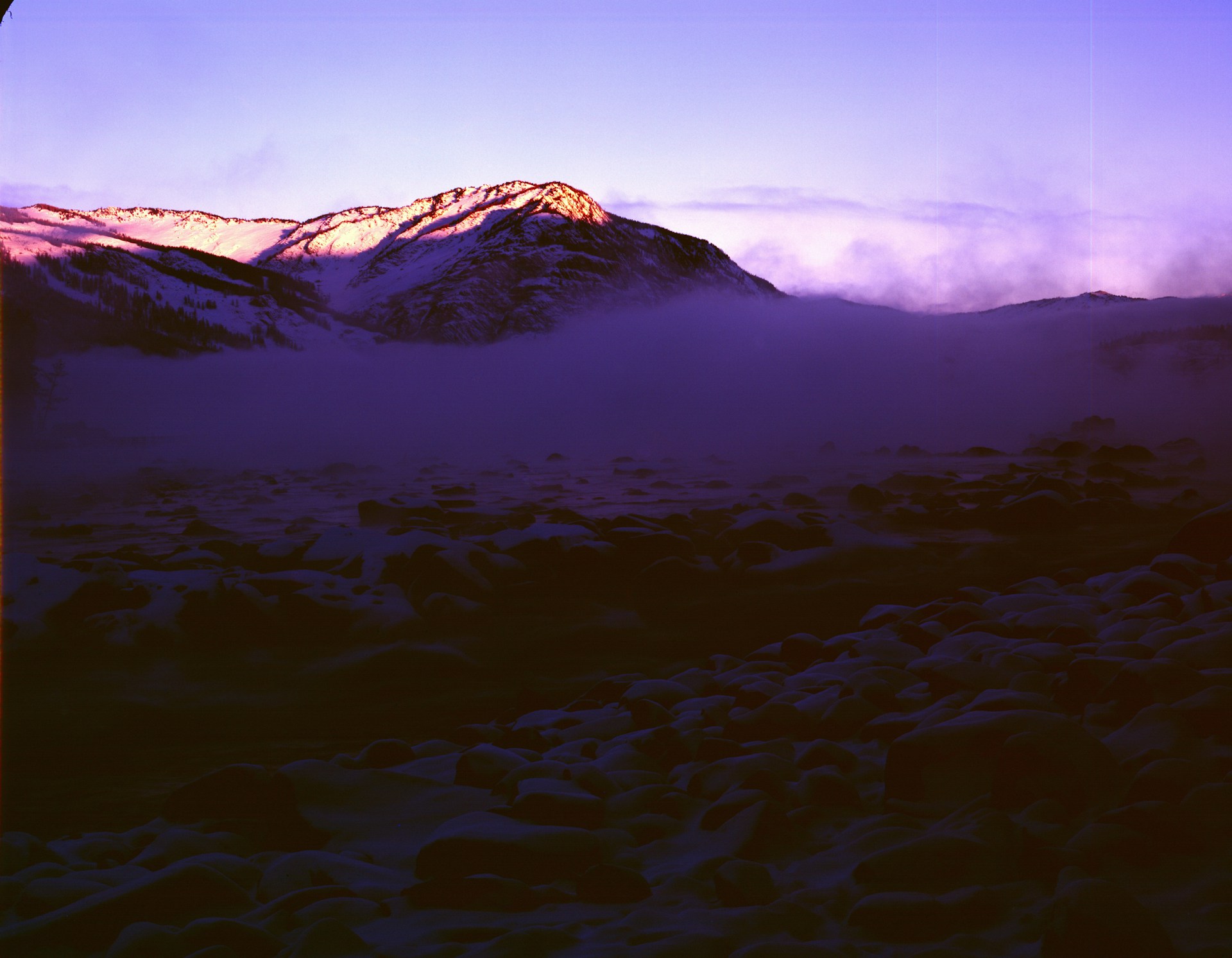 Golden hour light spilling over a misty mountain ridge, highlighting the delicate textures of the landscape.