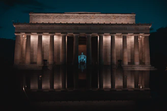 The Lincoln Memorial illuminated at night, reflecting in the calm pool.