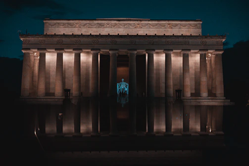 The Lincoln Memorial illuminated at night, reflecting in the calm pool.