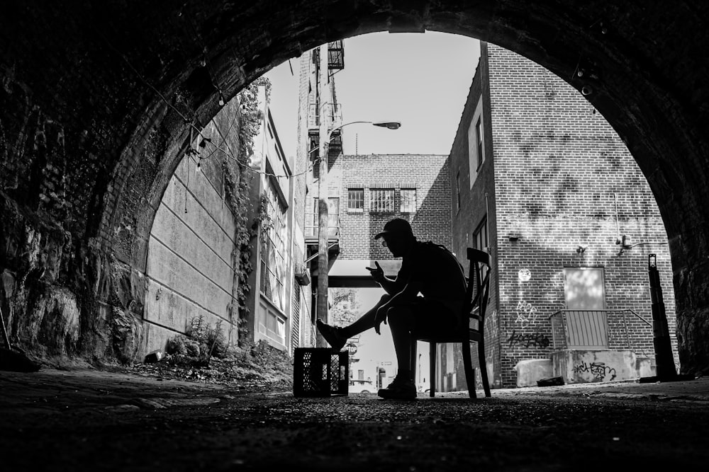 man in black t-shirt and black pants standing beside brick wall