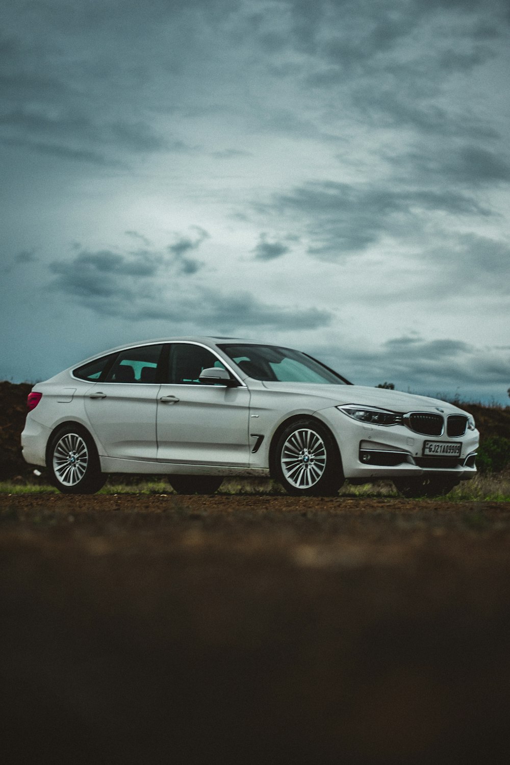 white bmw x 6 on brown field under white clouds during daytime