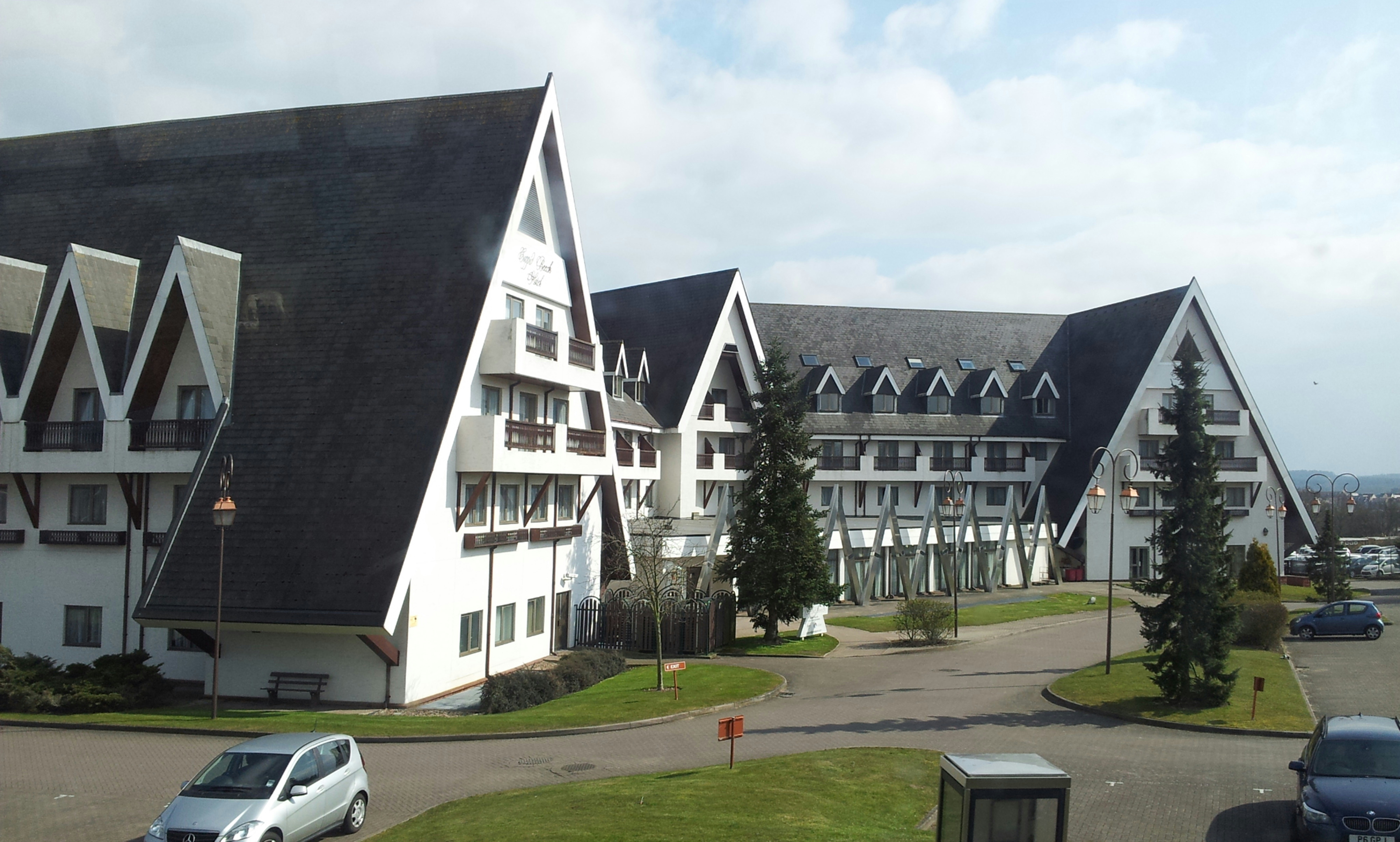 white car parked beside gray concrete building during daytime, 