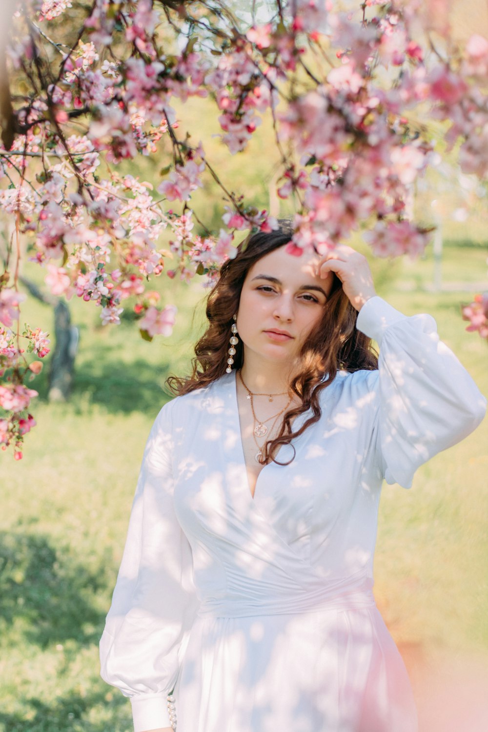 woman in white long sleeve shirt standing beside pink flowers during daytime